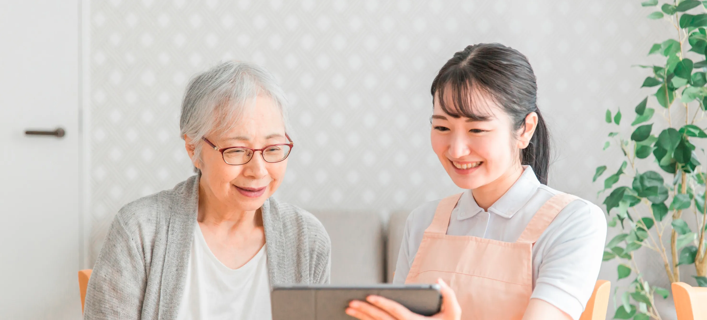 スタッフと入居者がタブレットを一緒に見ながら交流する様子